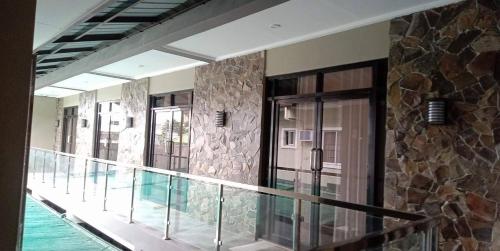 Un balcón con puertas de cristal y una pared de piedra. en Regal425 Condotel, en Ángeles