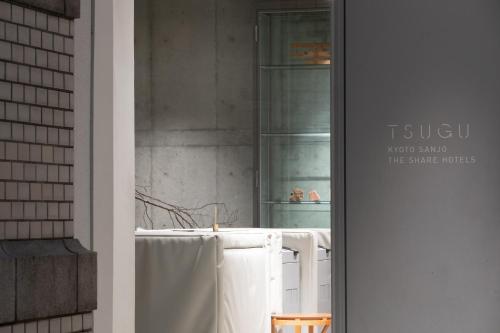 La salle de bains est pourvue de serviettes blanches suspendues à une fenêtre. dans l'établissement TSUGU Kyoto Sanjo by THE SHARE HOTELS, à Kyoto