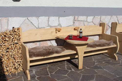 a wooden bench with a table and a bottle on it at Pension Lugeck in Berchtesgaden