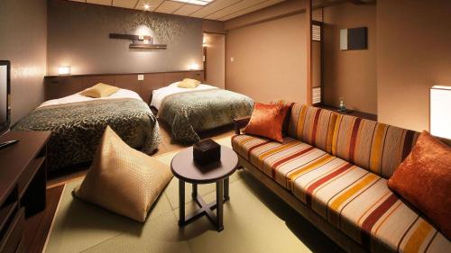 a hotel room with two beds and a couch at Kinugawa Onsen Hotel in Nikko
