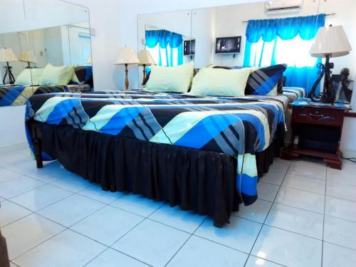 ein Schlafzimmer mit einem Bett mit einer blau-schwarzen Bettdecke in der Unterkunft Secure Gated 1BR Home in Caribbean Estate 2BR Also Available in Portmore