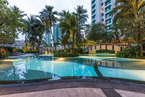 a large swimming pool with palm trees and buildings at Chatrium Sathon Bangkok in Bangkok