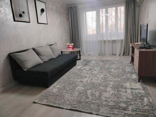 uma sala de estar com um sofá e uma televisão em Уютная 2 ком-я квартира в центре города, район "Арбата" em Almaty