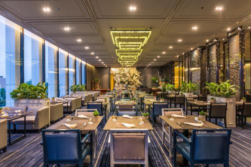 a dining room with tables and chairs and windows at Chatrium Sathon Bangkok in Bangkok