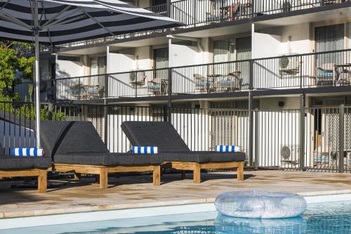 a swimming pool with two lounge chairs and a building at Kiama Shores in Kiama