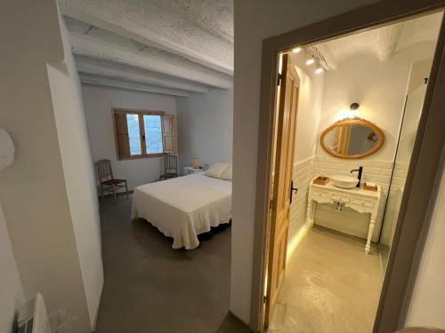 1 dormitorio con cama blanca y espejo en Cal Torrentó Apartaments, en Balaguer