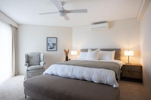 a bedroom with a large bed and a chair at Mariners 1 in Mollymook
