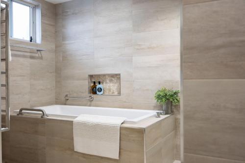 a bathroom with a bath tub and a window at Mariners 1 in Mollymook