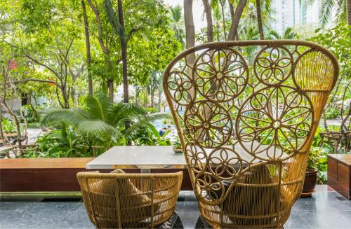 a table and two chairs and a table and trees at Chatrium Sathon Bangkok in Bangkok