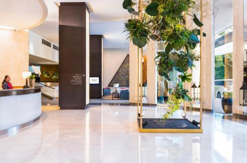 a lobby with a bunch of potted plants at Chatrium Sathon Bangkok in Bangkok