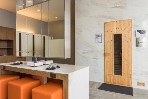 a lobby with a counter with orange stools and a mirror at Chatrium Sathon Bangkok in Bangkok