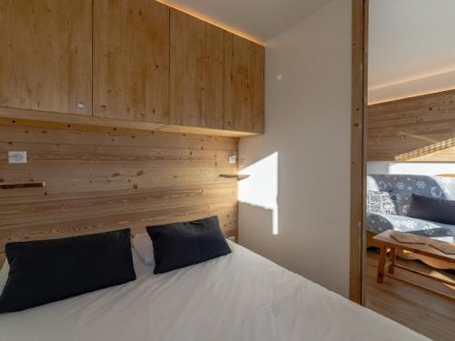 a bedroom with a white bed with a wooden wall at Appartement rénové proche des pistes avec WiFi et linge inclus - FR-1-640-10 in Val Thorens