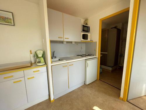 une petite cuisine avec des armoires blanches et un micro-ondes dans l'établissement Appartement 2 pièces avec terrasse, parking, proche plage et centre - FR-1-225D-179, à Saint-Cyprien