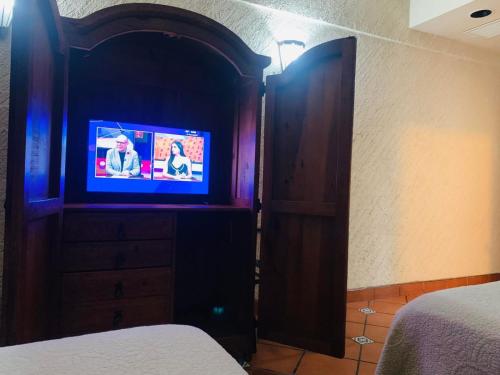 HOTEL COLONIAL MATAMOROS في ماتاموروس: غرفة نوم مع تلفزيون في خزانة خشبية