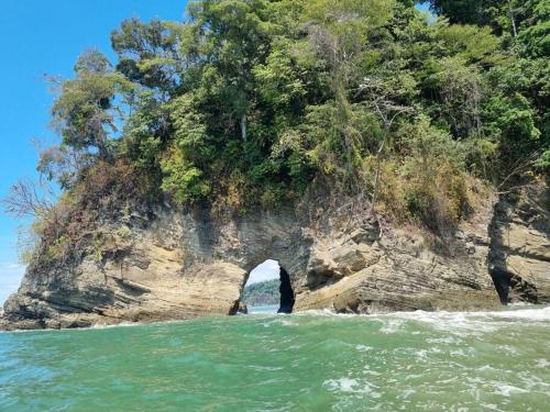an archway in the side of a rocky island in the water at Villa Amor del Mar with Breathtaking View of Ocean & Jungle in Dominical