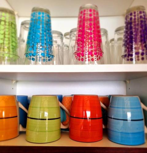 a row of colorful cups sitting on a shelf at Villa Amor del Mar with Breathtaking View of Ocean & Jungle in Dominical