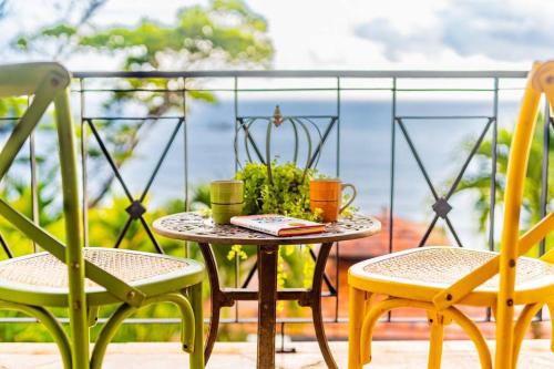 a table with two chairs and two cups on a balcony at Villa Amor del Mar with Breathtaking View of Ocean & Jungle in Dominical
