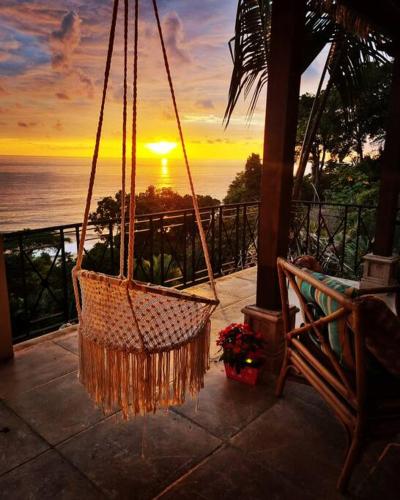 a hammock hanging from a porch with a view of the ocean at Villa Amor del Mar with Breathtaking View of Ocean & Jungle in Dominical