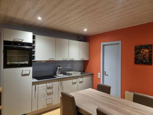 eine Küche mit einem Tisch und einem weißen Kühlschrank in der Unterkunft Le Rouge Gorge Curieux in Vresse-sur-Semois