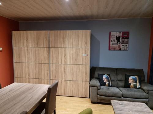 ein Wohnzimmer mit einem Sofa und einem Holzschrank in der Unterkunft Le Rouge Gorge Curieux in Vresse-sur-Semois