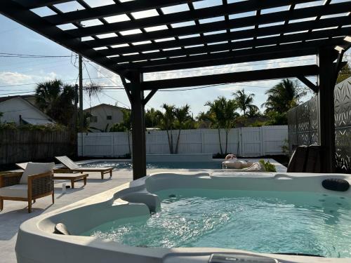 萊克沃思的住宿－Jungle Cottage with luxury pool, hot tub and more!，一个带热水浴池的游泳池,位于凉棚下