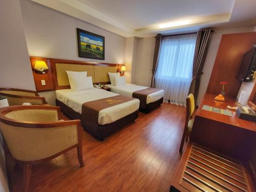 a hotel room with two beds and a desk at Aristo Saigon Hotel in Ho Chi Minh City