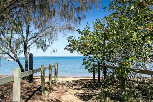 a wooden fence on the beach near the water at Boat Harbour Studio Apartments and Villas in Hervey Bay