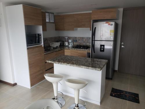 eine Küche mit einem Kühlschrank und einer Theke mit Stühlen in der Unterkunft Apartamento amoblado con excelente ubicación en Pasto in Pasto