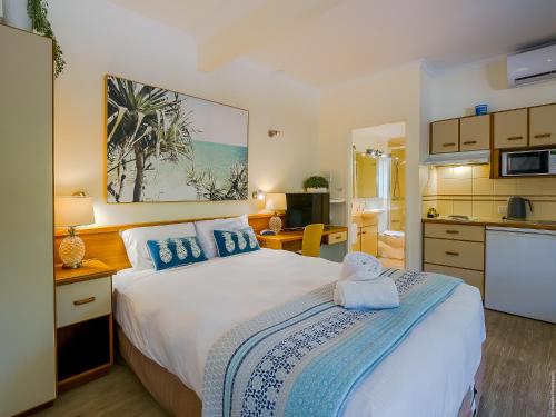 a bedroom with a large bed and a kitchen at Boat Harbour Studio Apartments and Villas in Hervey Bay