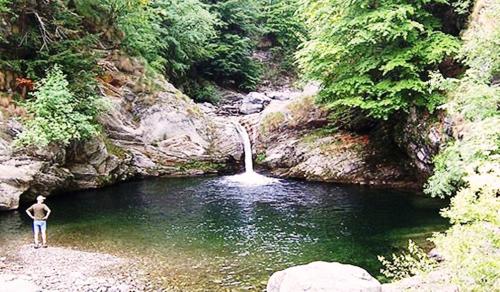 a man standing in the water next to a waterfall at Lakeview Cannobio Camping & Resort in Cannobio