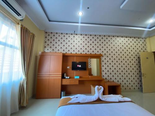 a bedroom with a bed and a desk and a tv at Wisma Jannatun Naim Lampung in Lampung