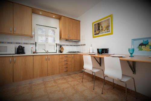 a kitchen with wooden cabinets and white chairs at Casa Adega - Quinta Amoreira in Faro