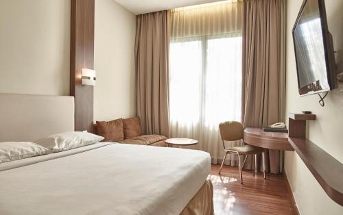Pokój hotelowy z łóżkiem i biurkiem w obiekcie Grand Cikarang Hotel w mieście Tegalgede