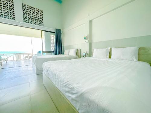 a white bedroom with two beds and a large window at Paradise Resort Doc Let - All Inclusive in Doc Let