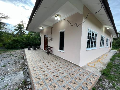 a white house with a patio with tables and chairs at Joe’s Homestay Raub Phg in Raub