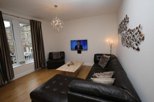 a living room with a leather couch and a table at Edinburgh Pearl Apartments - Dalry House Residence in Edinburgh