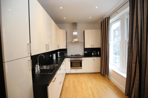 a kitchen with black and white cabinets and a window at Edinburgh Pearl Apartments - Dalry House Residence in Edinburgh