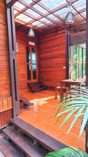 a porch of a wooden cabin with a table and benches at Areeya phubeach resort wooden house Coliving Coworking in Ban Chong Phli