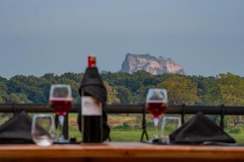 uma mesa com copos de vinho e uma cruz na montanha em Ceylon Breeze Sigiriya em Sigiriya