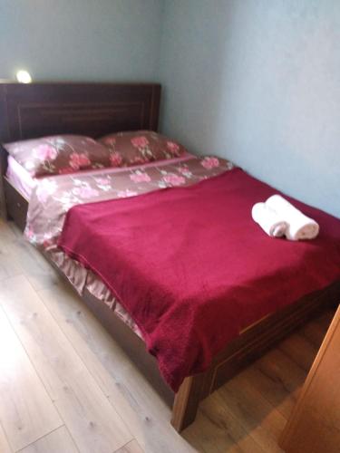 ein Bett mit einer roten Bettdecke und zwei Handtüchern darauf in der Unterkunft qood plase in Tbilisi City