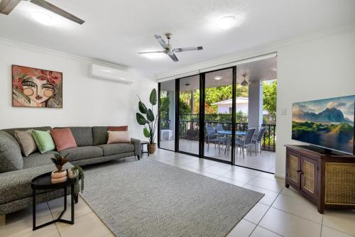 a living room with a couch and a tv at Elysium Apartments in Palm Cove
