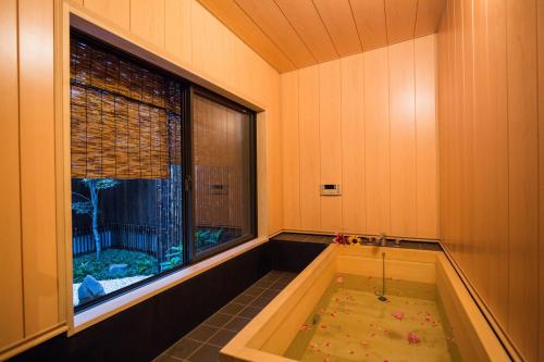 eine Whirlpool-Badewanne in einem Zimmer mit Fenster in der Unterkunft Kyomachi Yumeji in Kyoto