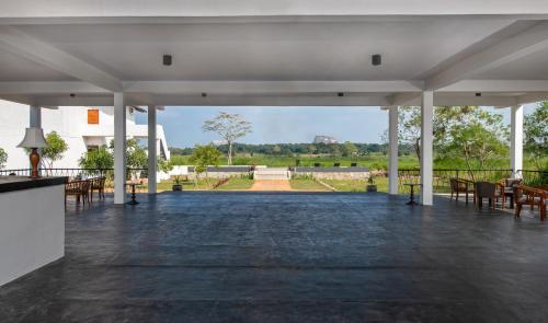 a pavilion with tables and chairs and a view of a park at Ceylon Breeze Sigiriya in Sigiriya