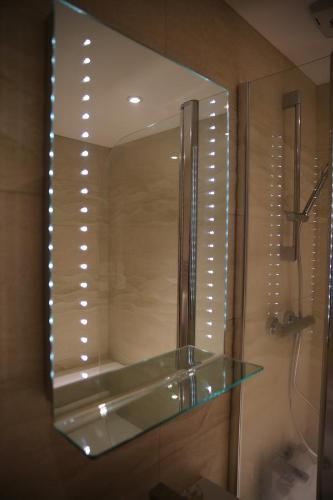 a mirror in a bathroom with a glass shelf at Dalry House Residence in Edinburgh