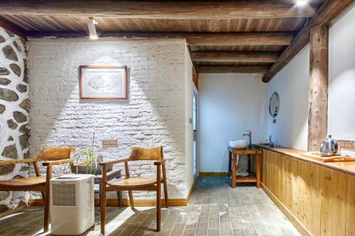 a room with a table and chairs and a brick wall at Yangshuo Yunshe Mountain Guesthouse in Yangshuo