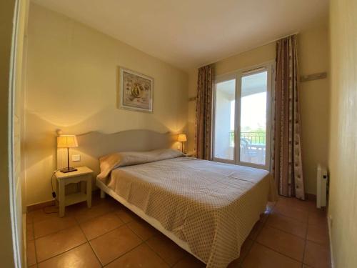 une chambre avec un lit et une grande fenêtre dans l'établissement Les Issambres, T2 avec piscine, parking sécurisé - FR-1-226-467, à Roquebrune-sur Argens