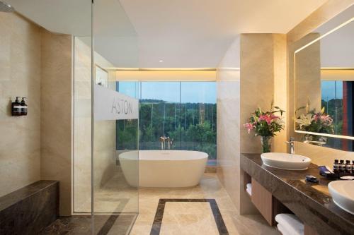 ASTON Sentul Lake Resort & Conference Center في بوغور: حمام به مغسلتين وحوض استحمام