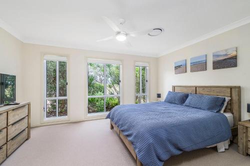 1 dormitorio con 1 cama azul y ventanas en Iluka Breeze, en Dunbogan
