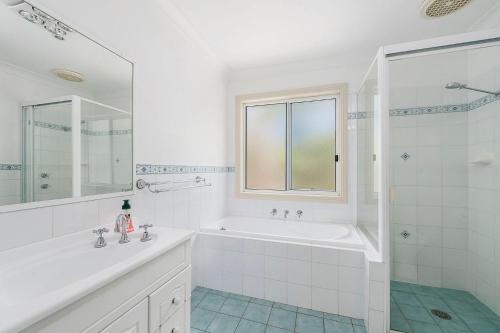 Un baño blanco con bañera y lavabo. en Iluka Breeze, en Dunbogan