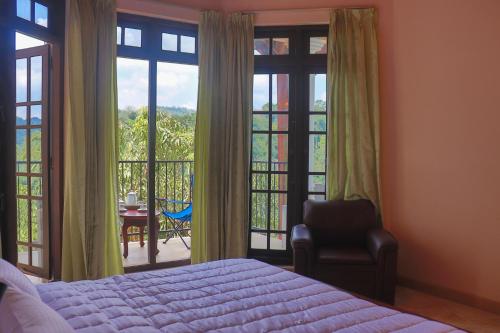 a bedroom with a bed and a chair and a balcony at Hideaway Homestay kandy in Haloluwa